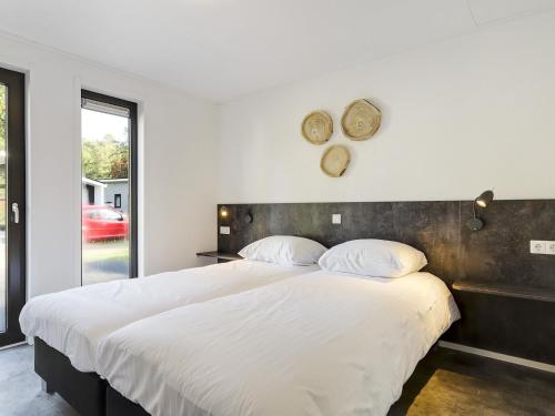 een slaapkamer met een groot bed met witte lakens bij Relaxing Forest Hideaway in Markelo