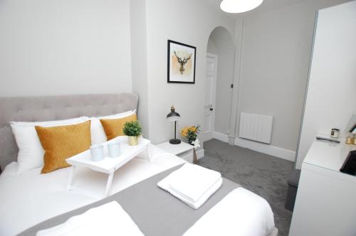 een witte slaapkamer met een groot wit bed met oranje kussens bij Modern One Bed Apartment, by Kipz City Centre Chester - Amazing Location & Quiet! in Chester