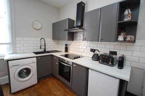 a kitchen with a sink and a washing machine at City Centre 1 Bed Apartment - Modern & Bright in Chester