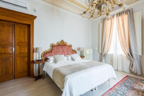 Un dormitorio con una gran cama blanca y una lámpara de araña. en Villa Savioli Room & Breakfast, en Bolonia