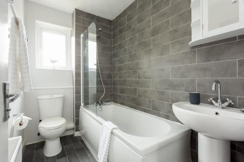 een badkamer met een wit bad, een wastafel en een toilet bij Solstice in Poole