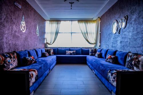 a living room with a blue couch in front of a window at Belle escale in Oujda