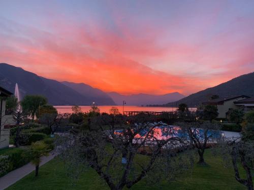 a sunset over a body of water with mountains at Ulivi Hotel & Residence in Paratico