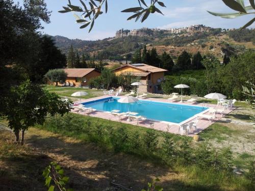 a pool with chairs and umbrellas in front of a house at Agriturismo Feudo Gagliardi in Caulonia