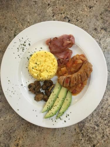 a plate of breakfast food with eggs bacon and vegetables at Asante Guest House in Vanderbijlpark