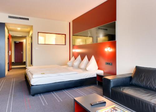 um quarto de hotel com uma cama e um sofá em Novina Hotel Herzogenaurach Herzo-Base em Herzogenaurach