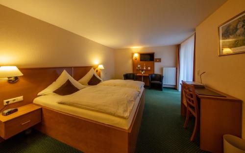 バイルシュタインにあるHotel Burgfriedenの大きなベッドとデスクが備わるホテルルームです。