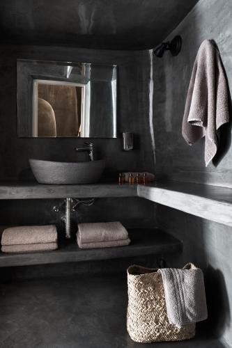 a bathroom with a sink and a mirror and towels at Virginia's Cave Villas in Oia