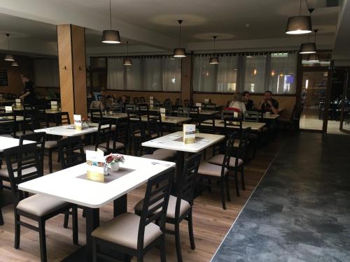 a restaurant with white tables and chairs and people sitting at tables at Tatralandia-Liptov Chatky in Liptovský Mikuláš
