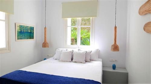 a bedroom with a white bed with a blue blanket and two windows at 30villa Rd in Rhodes Town