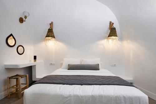 ein Schlafzimmer mit einem Bett mit zwei Lichtern an der Wand in der Unterkunft Virginia's Cave Villas in Oia