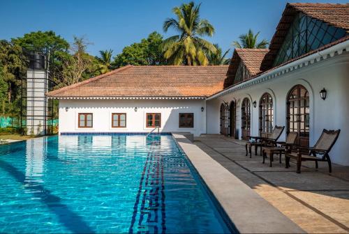 a swimming pool in front of a house at The Postcard Cuelim, Goa in Cansaulim