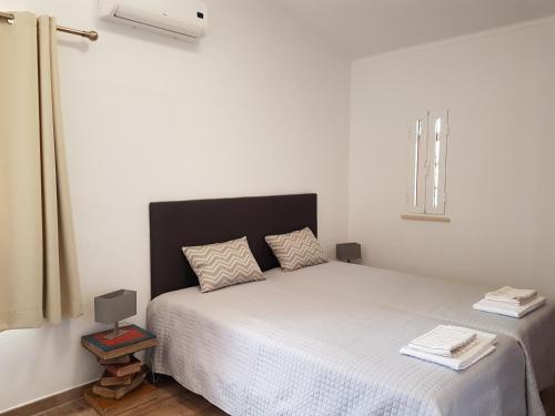 a bedroom with a white bed with a black headboard at Vila Caixinha in Armação de Pêra