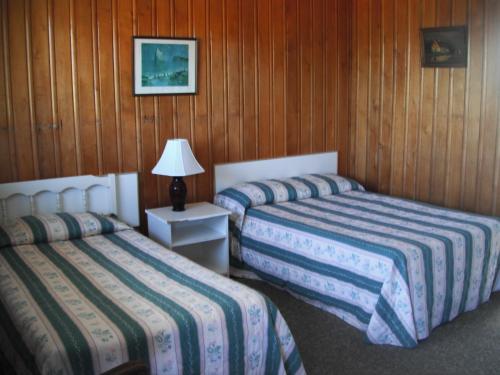two beds in a room with wood paneled walls at Motel Seal Rock in Perce