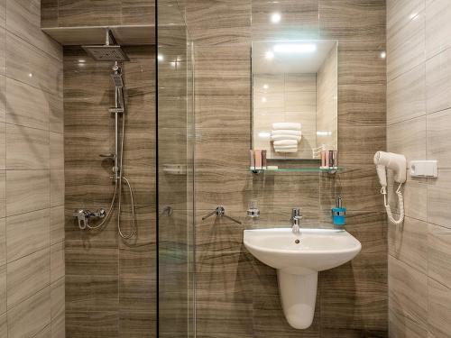 La salle de bains est pourvue d'un lavabo et d'une douche en verre. dans l'établissement Hotel Olympia Česká Lípa, à Česká Lípa