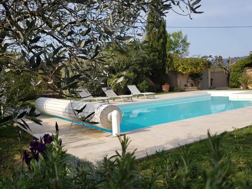 a swimming pool with lounge chairs next to a house at La Parenthèse in Lauris