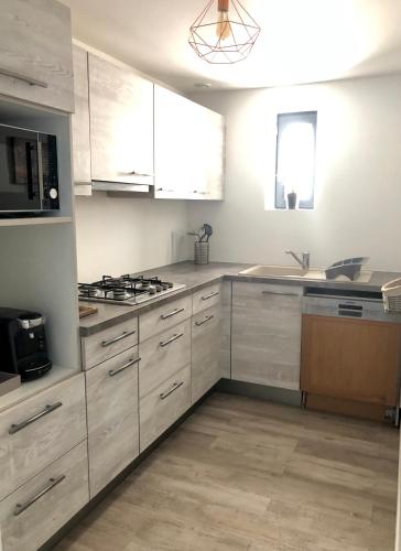 une cuisine avec des armoires blanches et un four à plaques de cuisson dans l'établissement VILLA BIRDS, à Boran-sur-Oise