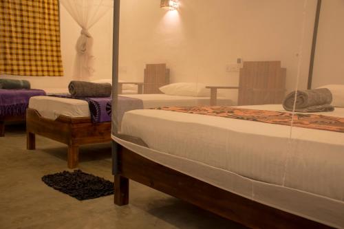 Habitación con 2 camas y espejo. en Eagle Resort Arugambay, en Arugam Bay