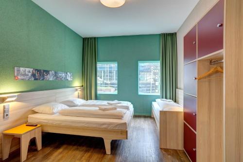 a bedroom with two beds and green walls at MEININGER Hotel Amsterdam City West in Amsterdam