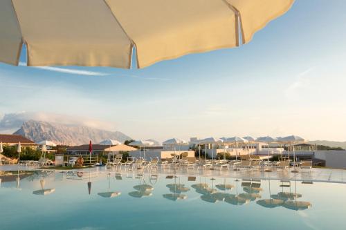 a view of a pool with chairs and an umbrella at Grande Baia Resort & Spa in San Teodoro