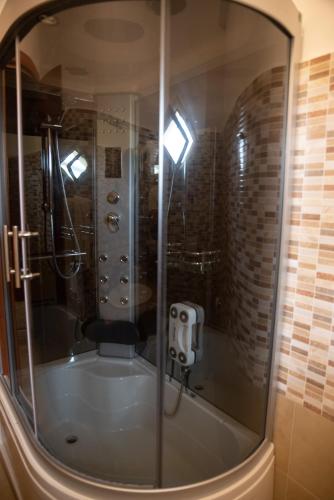a bath tub with a shower with a glass window at Hotel Royal Free Parking in Coccorino