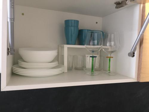 un estante blanco con platos y vasos. en Casa do Muro, en Coímbra