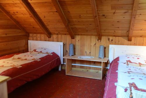 two beds in a room with wooden walls and wooden ceilings at Partie de chalet in Saint-Chaffrey