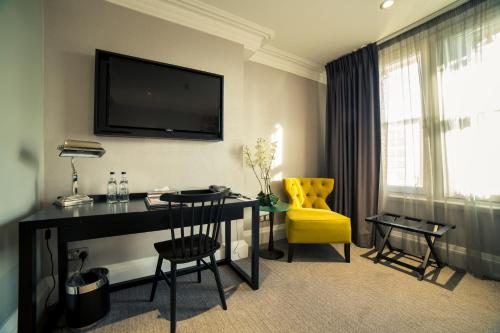 a hotel room with a desk and a yellow chair at Grey Street Hotel in Newcastle upon Tyne