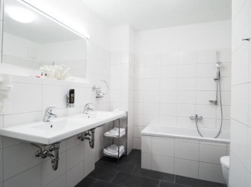 a white bathroom with two sinks and a bath tub at AlpenParks Chalet & Apartment AreitXpress in Zell am See
