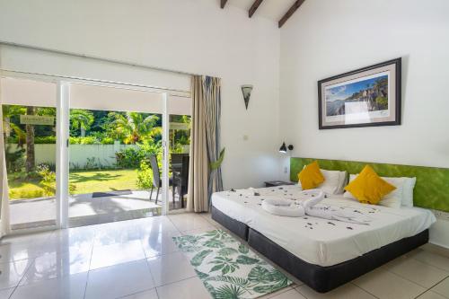 a bedroom with a large bed and a large window at La Modestie Guest House in Grand'Anse Praslin