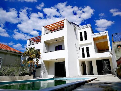 uma casa branca com uma piscina em frente em Apartments STAR with Pool em Biograd na Moru