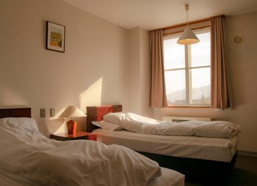 two beds in a hotel room with a window at La Vista Hotel Tsugaike - Stay on the Slopes in Otari