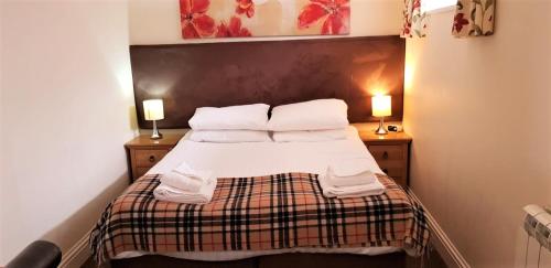 a small bedroom with a bed with two lamps at The Harbour House Sea front Hotel in Portpatrick