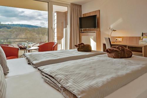 two beds in a hotel room with a balcony at Hotelpark der Westerwald Treff in Oberlahr