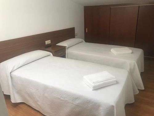 a room with two beds with white sheets at Pensión CHE in O Pedrouzo
