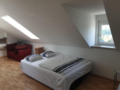 a bedroom with a bed and a red chair at Ferienwohnungen Kres in Gamlitz