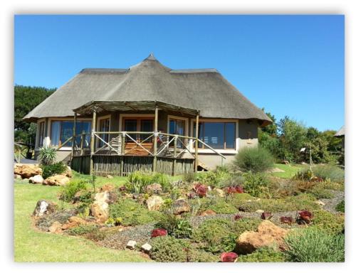 a large house with a thatched roof in a garden at ROCKY ALOE LODGE in Krugersdorp