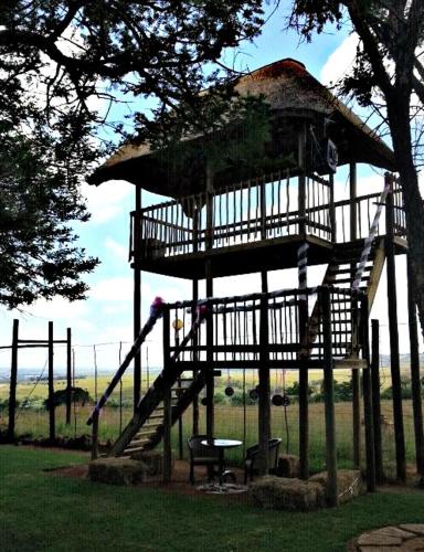 a large wooden gazebo with a table and a tree at Rocky Aloe Escape in Krugersdorp