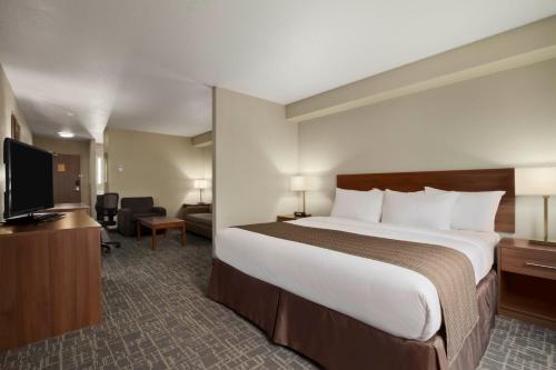 a hotel room with a bed and a flat screen tv at Days Inn & Suites by Wyndham Yorkton in Yorkton