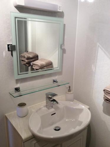 a white bathroom with a sink and a mirror at BORD DE L’EAU APARTMENT in Wick