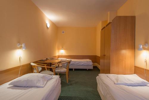 a hotel room with two beds and a table at Hotel ROK in Krakow