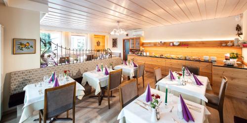 a restaurant with white tables and chairs and a bar at Hotel Tiffany in Merano