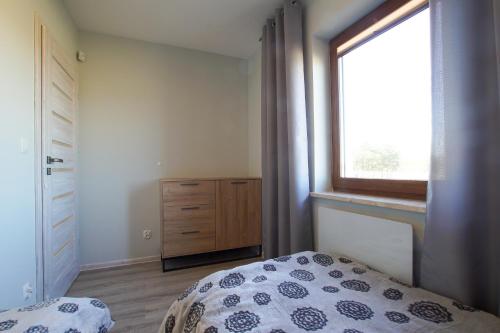 1 dormitorio con cama, ventana y vestidor en Magnolia, en Wilków