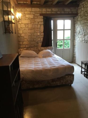 FresvilleにあるMaison de marie-claireのレンガの壁に大きなベッドが備わるベッドルーム1室が備わります。