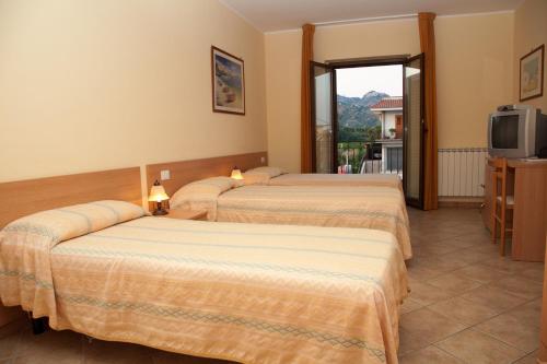 a hotel room with three beds and a television at Caffè Nuovo 2 Holiday Rooms in Trappitello