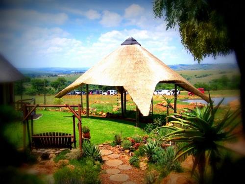 a large straw umbrella in a yard with plants at Rocky Aloe Escape in Krugersdorp