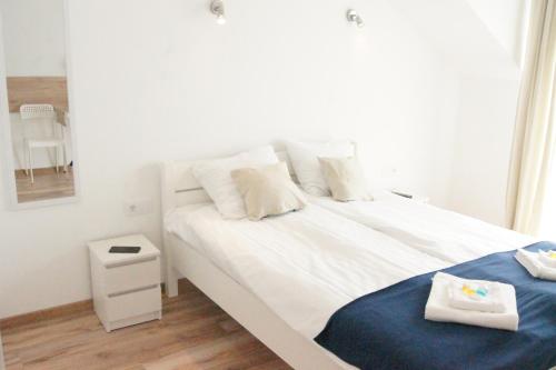 a bedroom with a large white bed with a blue blanket at Willa Wena in Ustka