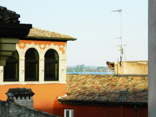an orange building with a tile roof with a antenna at MoAA - Modern Art Apartment in Desenzano del Garda
