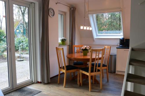 een eetkamer met een tafel en stoelen en een raam bij Calluna151 in Harfsen