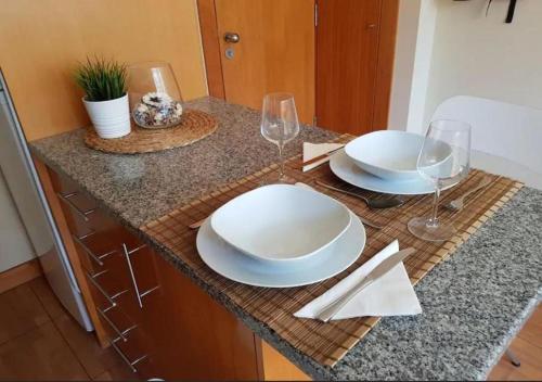 a table with two white plates and wine glasses at Cosy Santa Catarina Flat in Porto